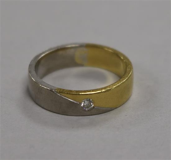 An 18ct white and yellow gold wedding band, set with a small diamond, 8.8g, size R.